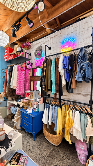 Montgomerie Gray Boutique at The Franklin Shops in Fort Myers, with royal-blue dresser, clothing displays and Long Live Cowgirls neon sign